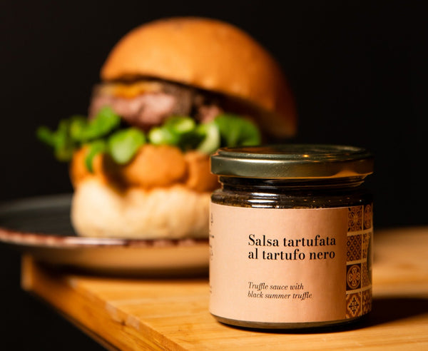 Jar of Salsa tartufata al tartufo nero with a blurred burger in the background