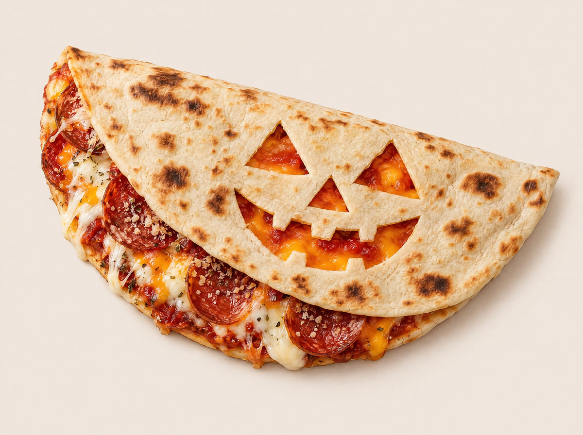 A piadina carved into a jack-o'-lantern, filled with melted cheese and pepperoni